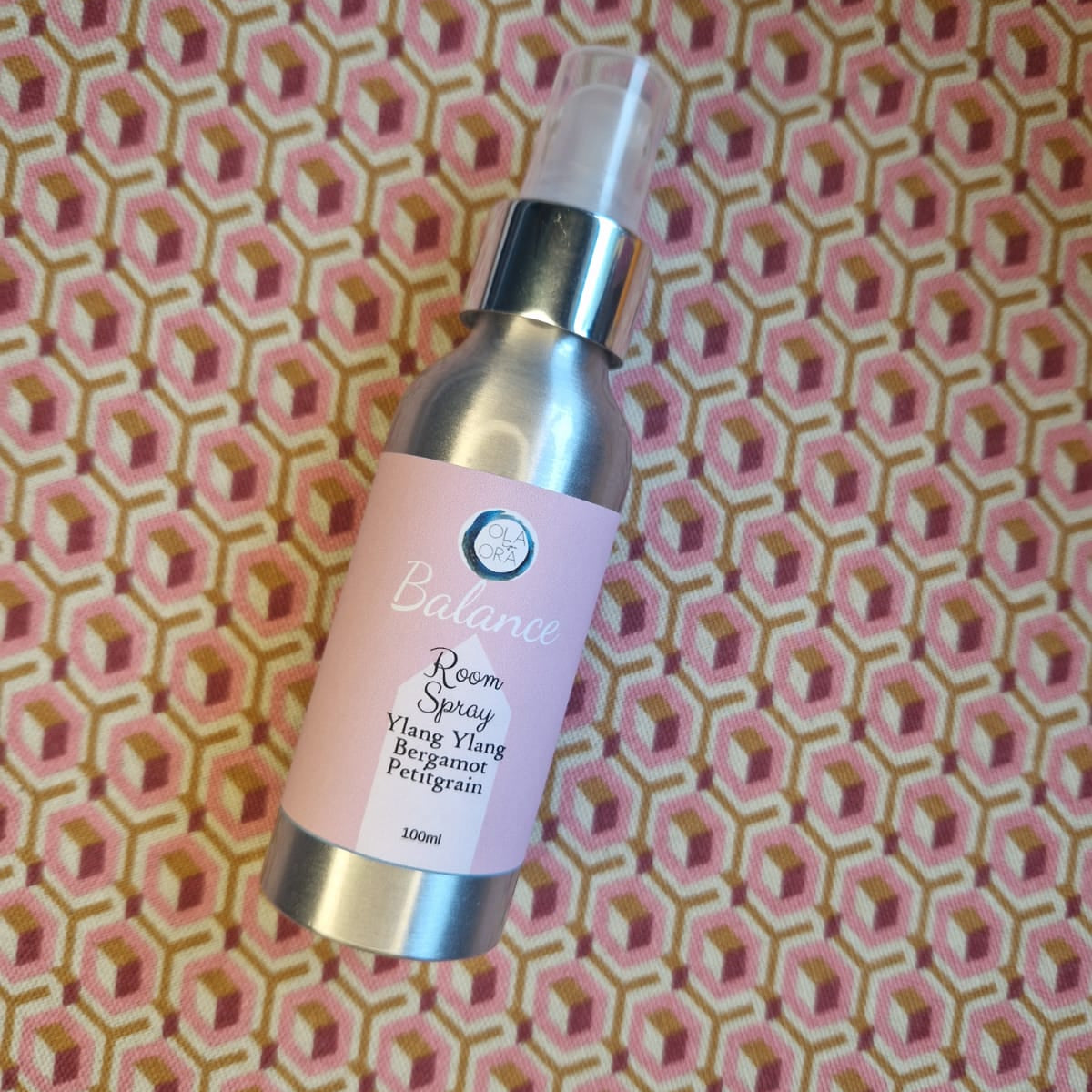 Skincare serum bottle with pink label on a patterned background