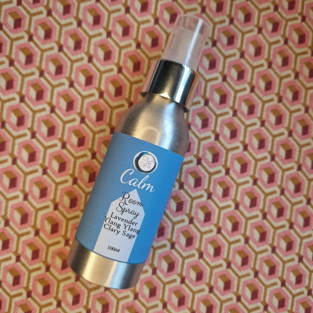 Bottle of 'Calm' spray on a patterned fabric background
