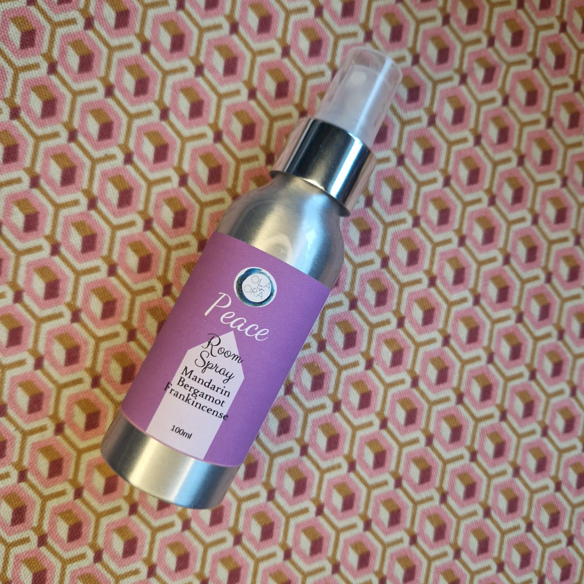 Skincare serum bottle with purple label on a patterned fabric background