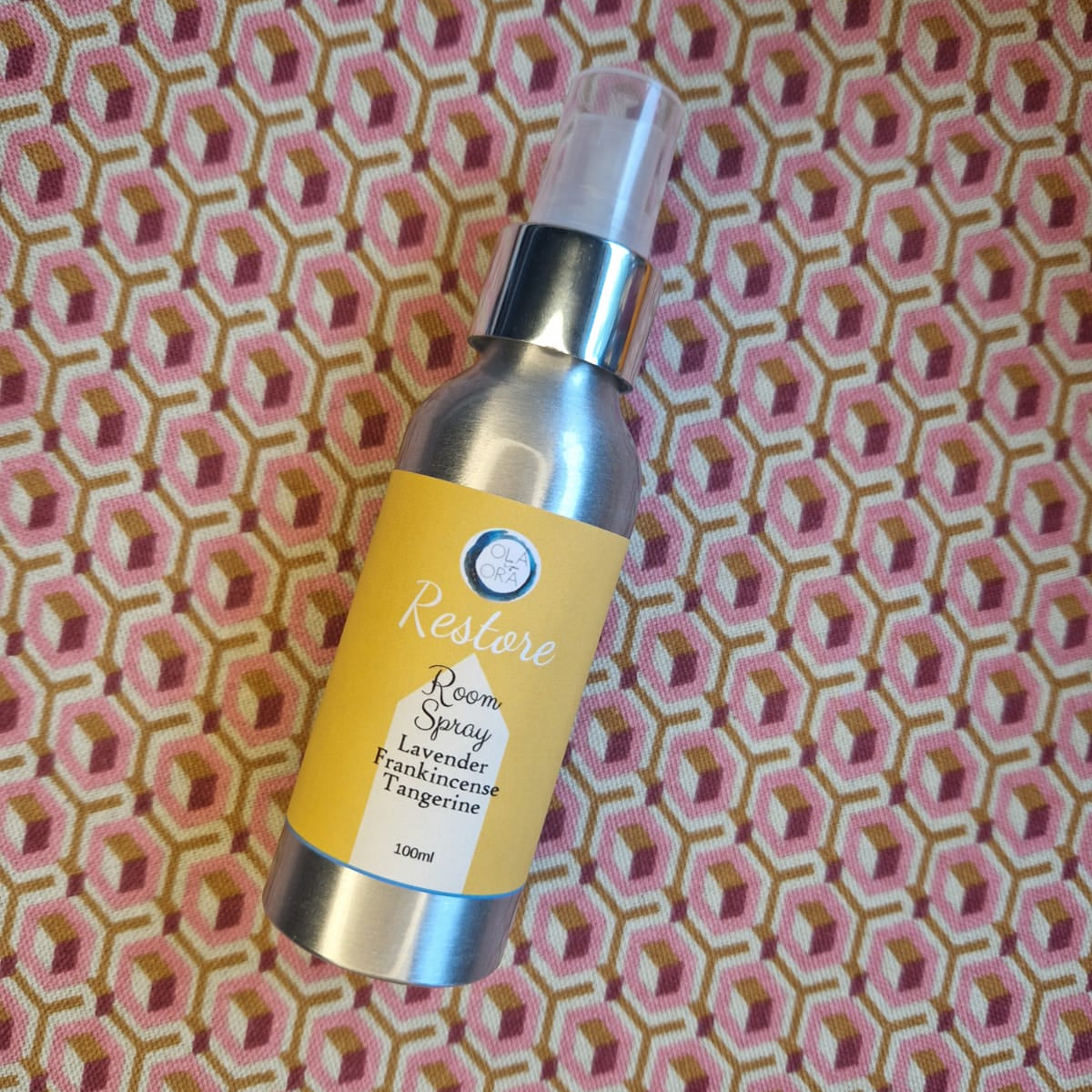 aromatherapy room spray bottle with yellow label on a patterned fabric background