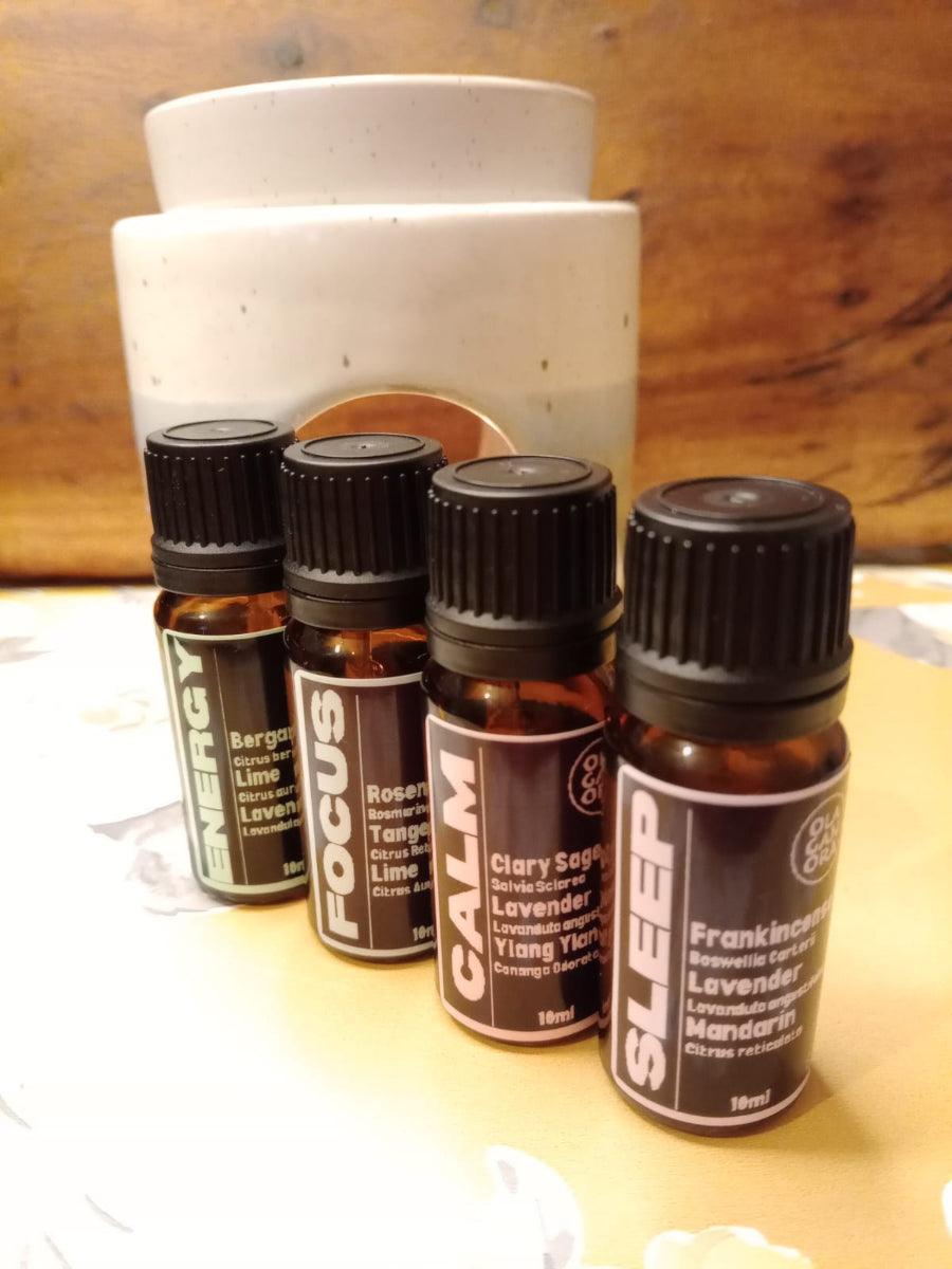 Four Bottles of Aromatherapy diffuser oils in front of a ceramic diffuser