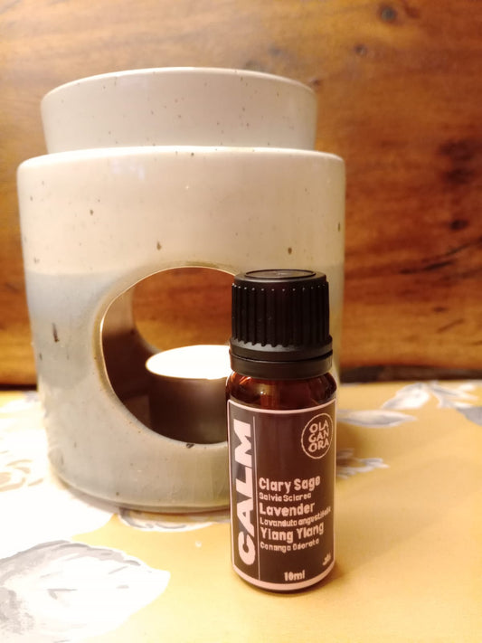 Calm aromatherapy diffuser oil blend in an amber bottle in front of a ceramic oil diffuser