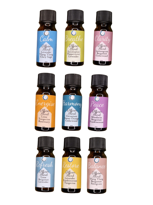 Nine small essential oil diffuser bottles arranged in a 3-by-3 grid on a plain white background. Each bottle has a black cap and a colorful label with a different scent name: Calm, Breath, Clarity, Energize, Harmony, Peace, Refresh, Resilience, and Balance.