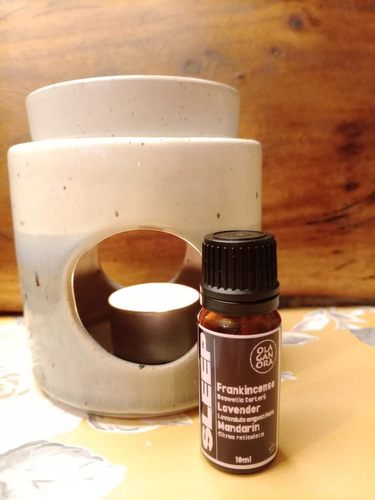 Sleep Aromatherapy Diffuser Oil in an amber bottle in front of a ceramic oil burner The blend contains Frankincense, Lavender and Mandarin Essential oils.