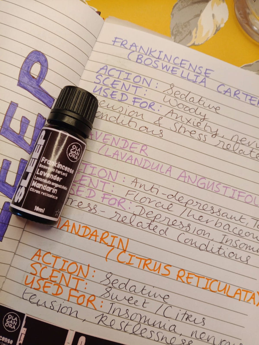 Sleep Aromatherapy Diffuser Oil in an amber bottle with a notebook of hand written notes about the oils Frankincense, Lavender and Mandarin Essential oils.